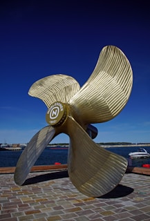 a large metal propeller sitting on top of a brick walkway