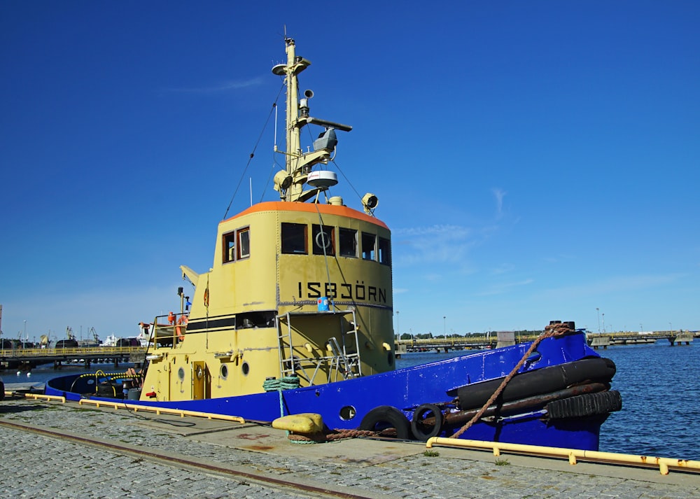a large yellow and blue boat sitting on top of a body of water