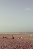 A group of kite surfers preparing their gear on a sandy beach at sunrise.