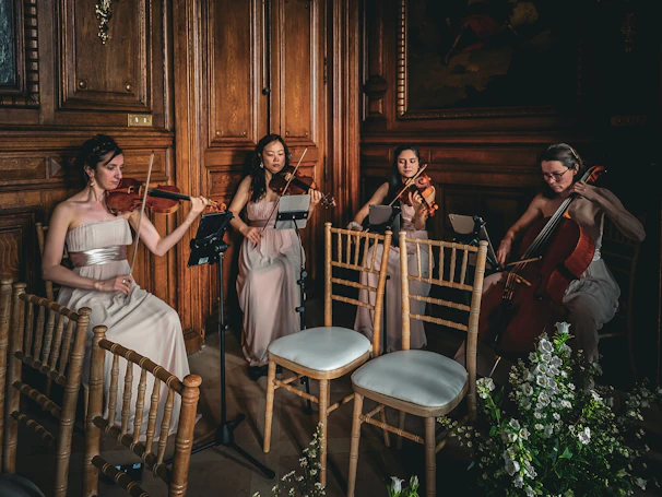 An elegant string quartet playing at a sunset wedding overlooking a serene garden