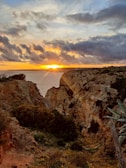 A stunning sunset over a rugged coastline with crashing waves.