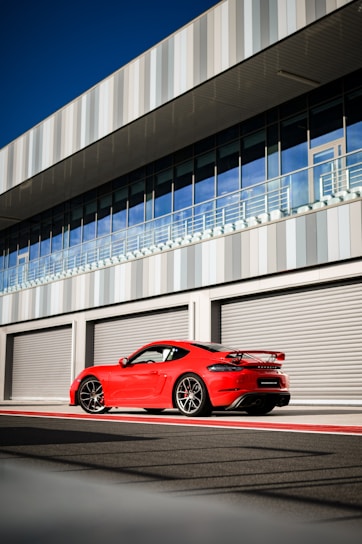 A sleek red and black GT Cars rental vehicle parked in front of a modern office building.