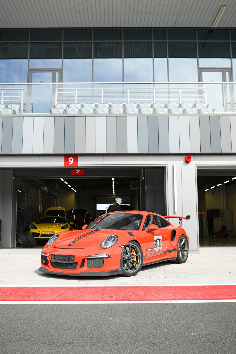 an orange sports car parked in front of a garage