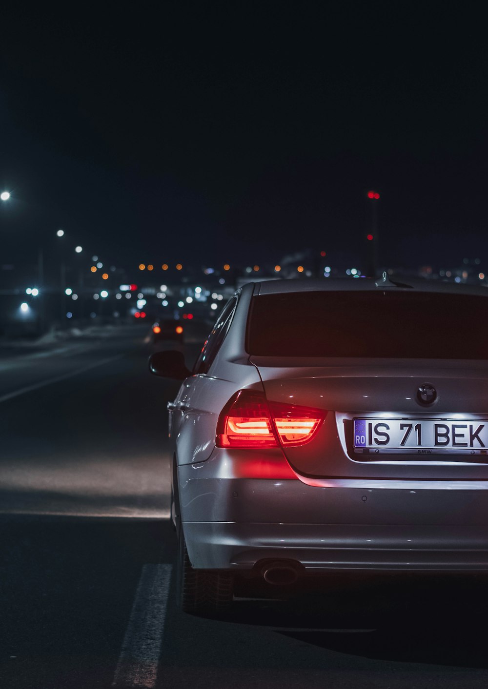 Un coche plateado aparcado al lado de la carretera por la noche