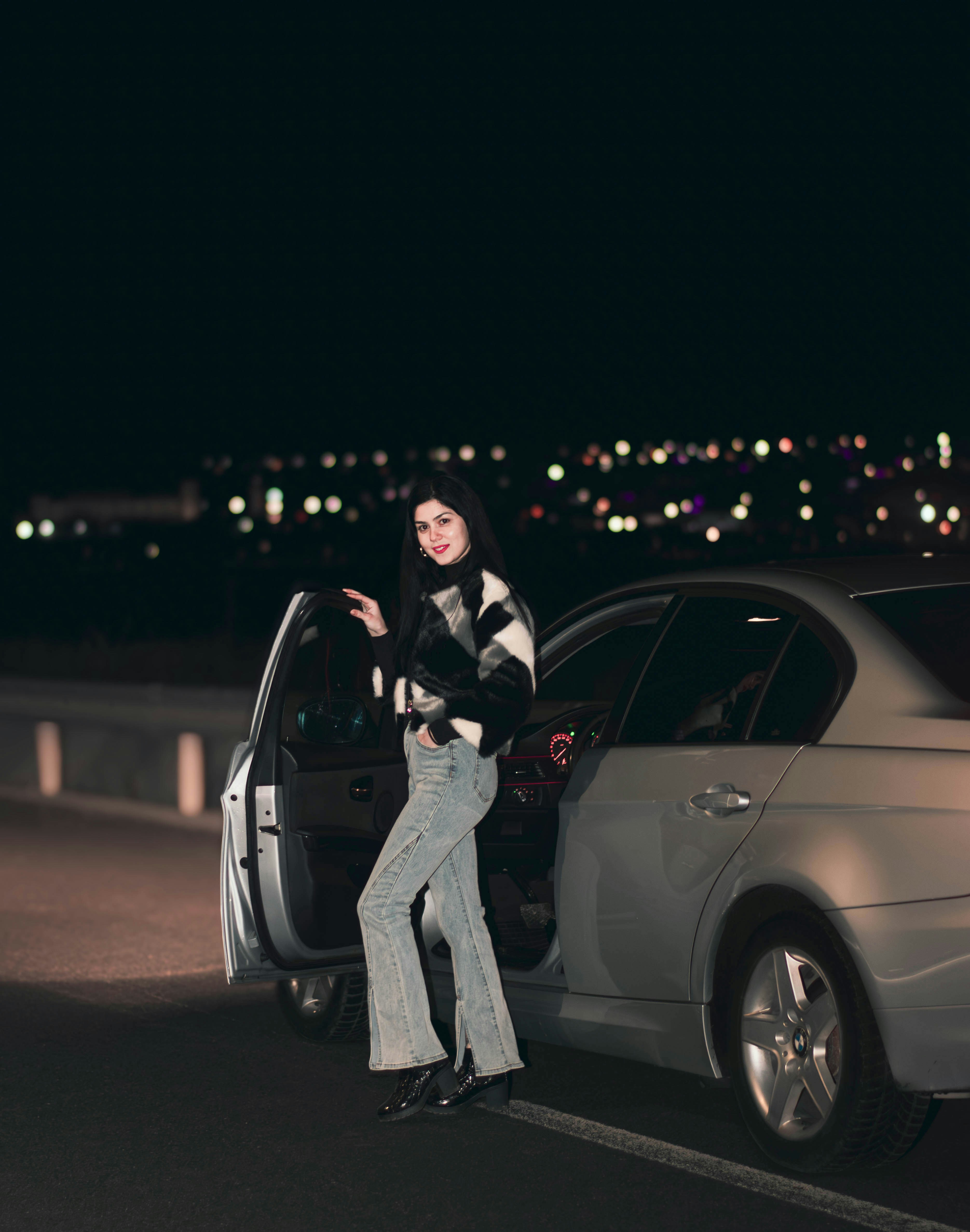 a woman standing next to a parked car