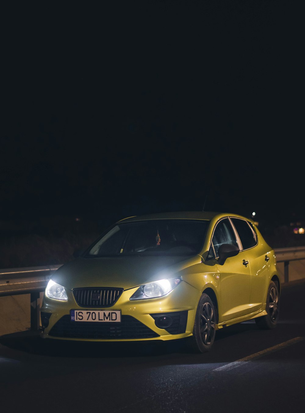 a yellow car driving down a road at night