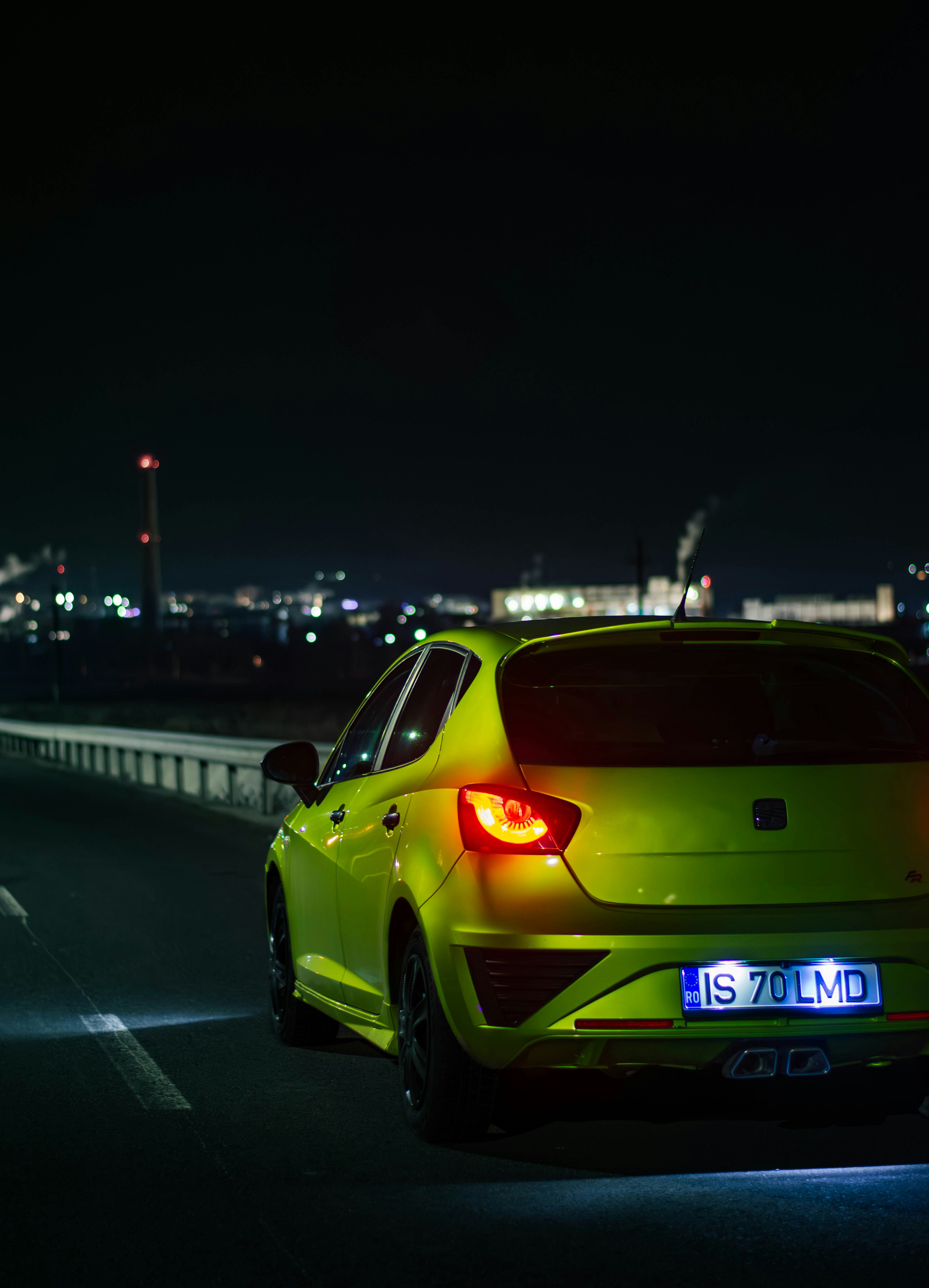 a yellow car driving down a road at night