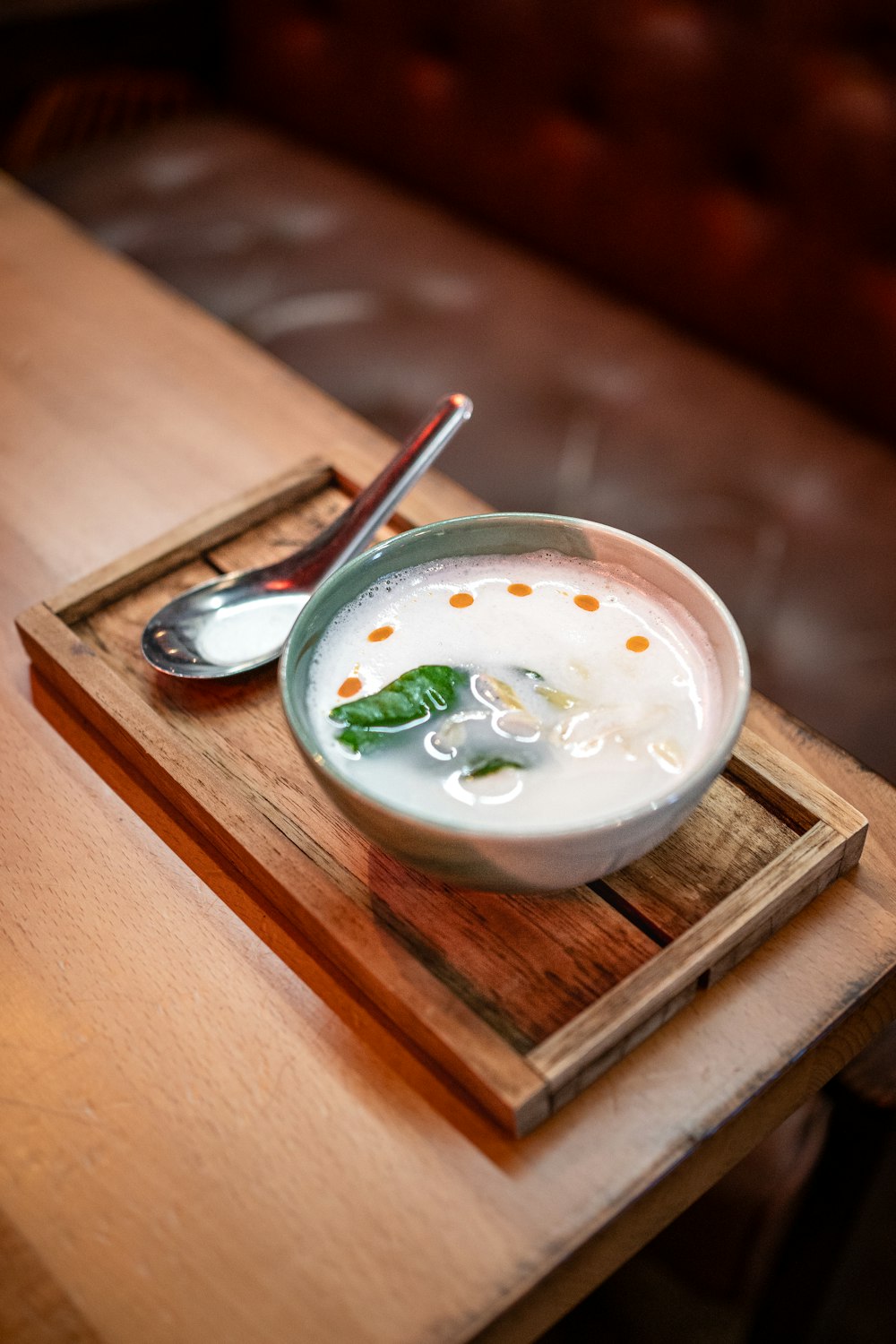 a bowl of milk and a spoon on a wooden tray