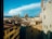 A scenic view of an Italian city with historical architecture, featuring red-tiled rooftops and the prominent dome of a cathedral against a clear blue sky.