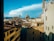 A scenic view of an Italian city with historical architecture, featuring red-tiled rooftops and the prominent dome of a cathedral against a clear blue sky.