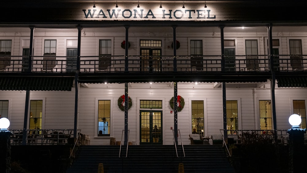 Un hotel por la noche con las luces encendidas y coronas de flores en la parte delantera