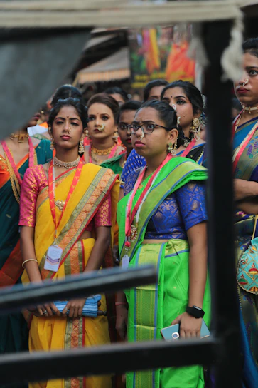 A vibrant display of women wearing elegant cotton sarees in a sunlit Kerala courtyard.