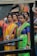 A group of women dressed in colorful traditional attire, including sarees, featuring vibrant colors like yellow, green, and blue. They accessorize with jewelry, such as necklaces and earrings. Some of them wear spectacles and badges around their necks. The background is blurred, suggesting a lively outdoor setting.