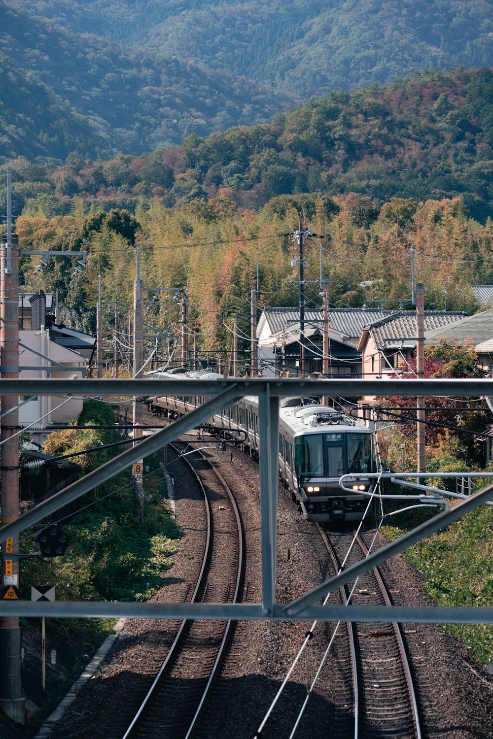 a train traveling down train tracks next to a lush green hillside