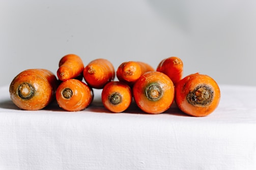 Bright orange baby carrots neatly arranged on rustic wooden surface.