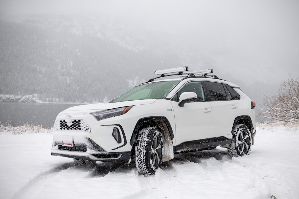 a white suv is parked in the snow