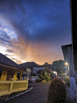A warm Sicilian sunset over a rustic village street filled with vibrant colors and soft light.