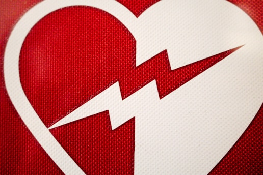 A white heart shape with a zigzag line splitting it in half is placed against a textured red background.