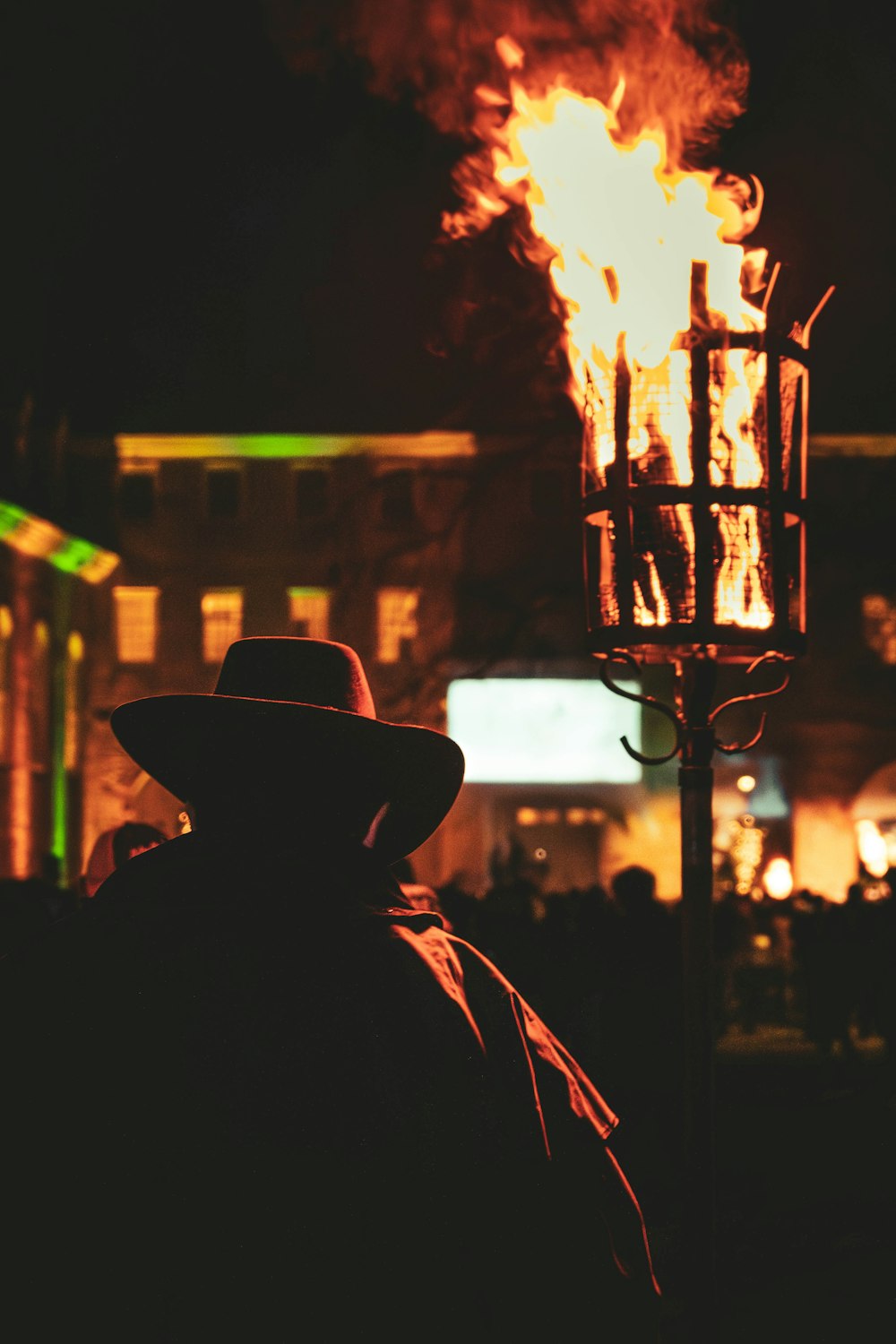 a man wearing a hat standing next to a fire