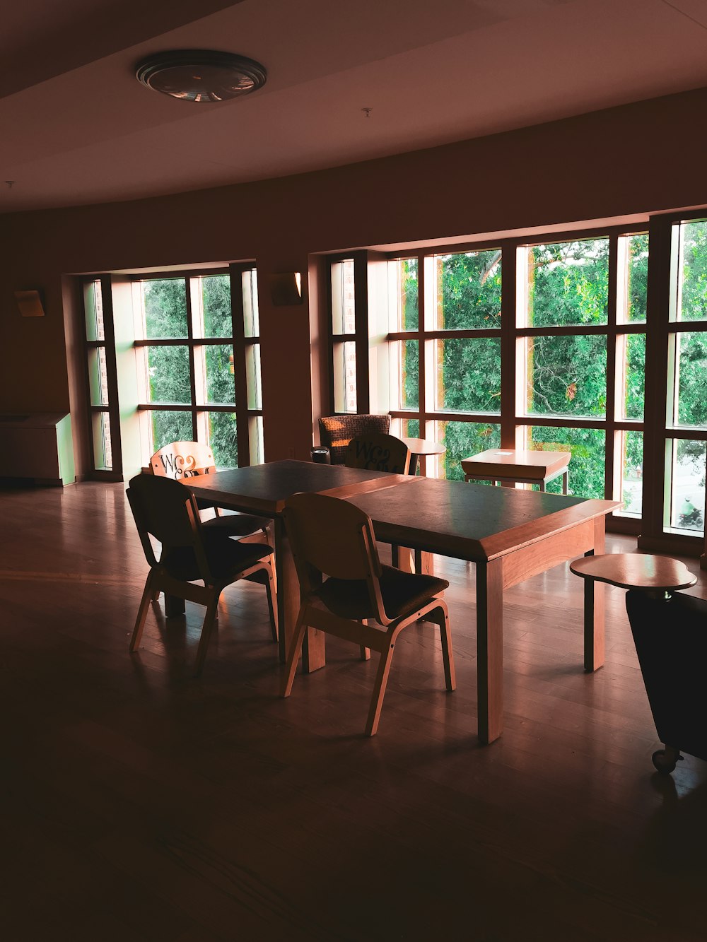 a room with a table, chairs, and large windows