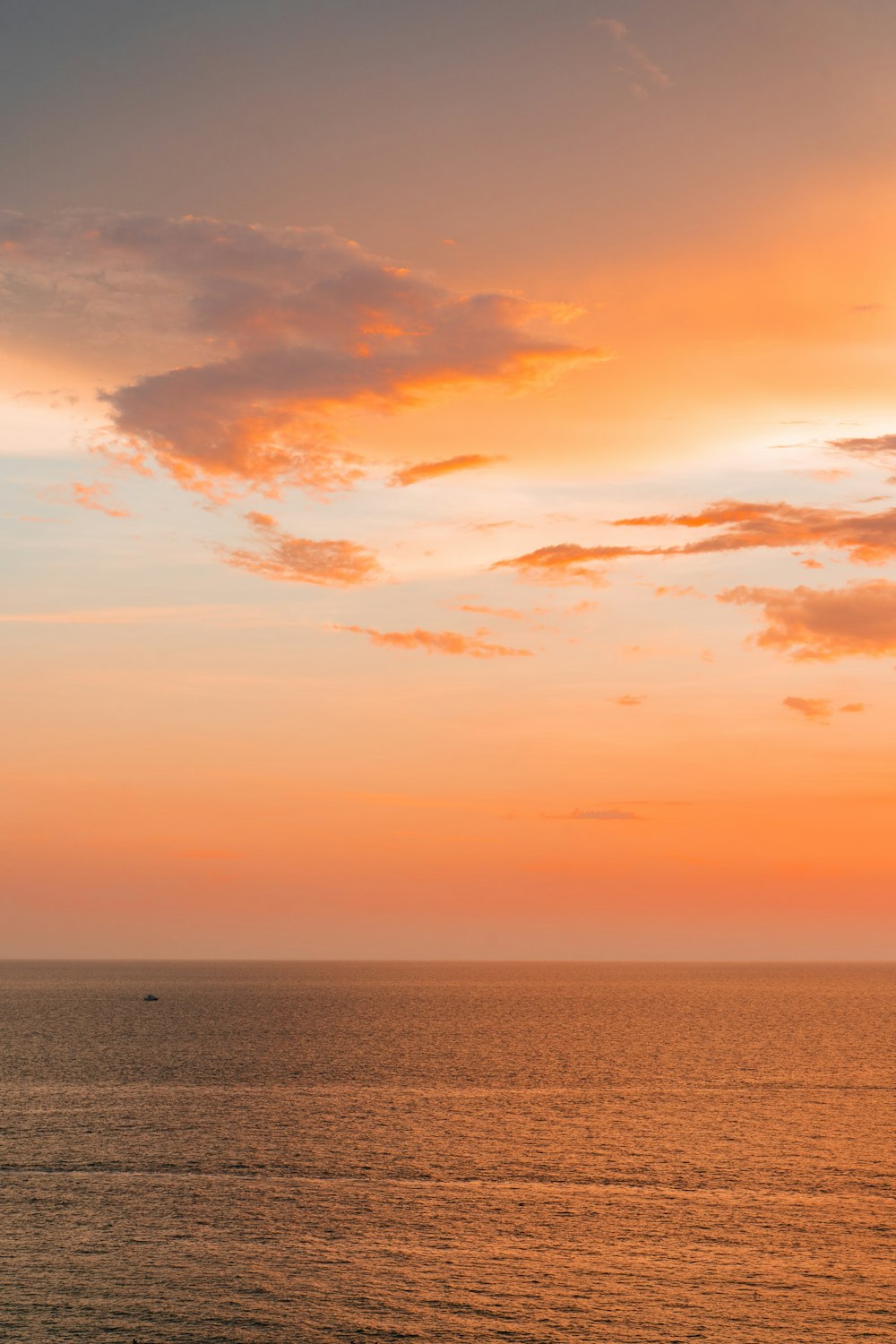 a sunset over the ocean with a boat in the distance