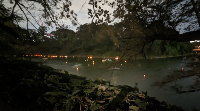 A serene evening view of the Ganga river with diyas floating gently on the water, framed by ancient temple silhouettes.