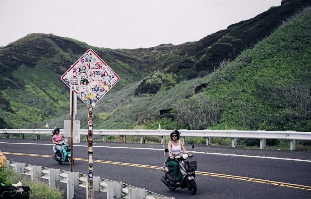 Un par de personas montando scooters por una carretera