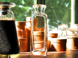 Artisan carefully inspecting a handcrafted glass bottle in a sunlit workshop.