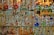 A collection of colorful glass and crystal items is displayed on multiple shelves. The objects vary in shape and include bottles, animal figurines, and decorative pieces. The glassware reflects light, creating a shimmering effect.