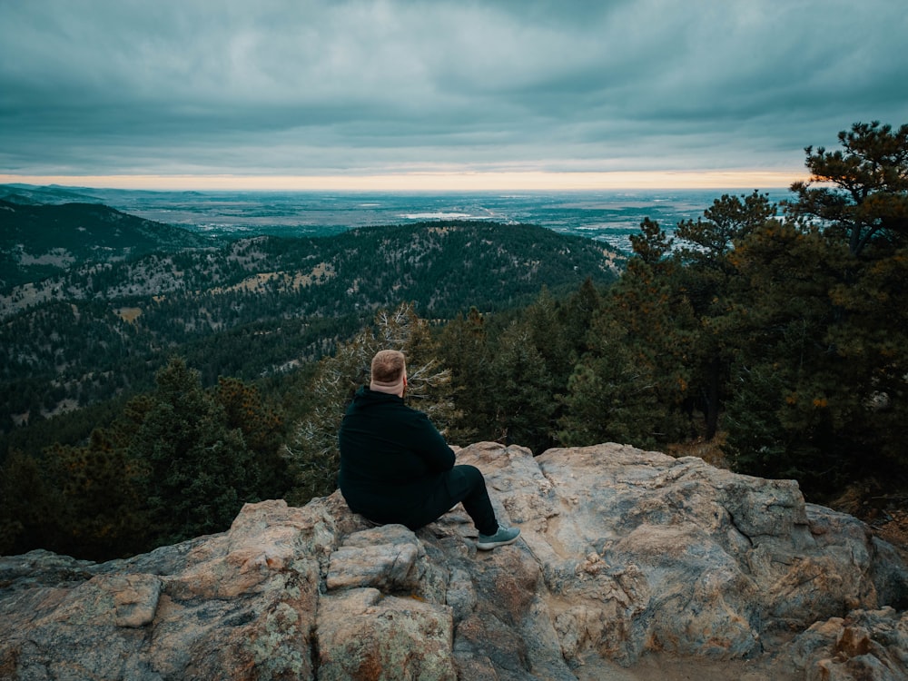 a man sitting on top of a large rock