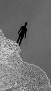 A haunting silhouette of a figure standing at the edge of a cliff.