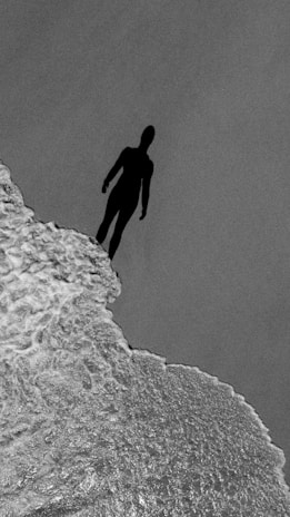 A haunting silhouette of a figure standing at the edge of a cliff.