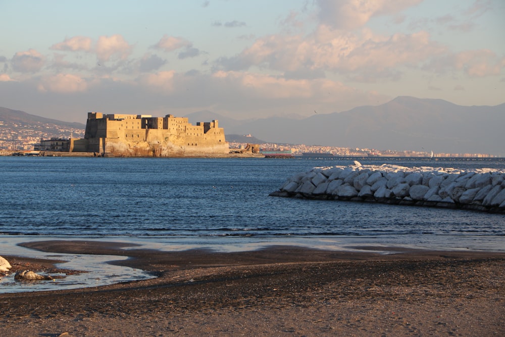Un château assis au sommet d’une plage à côté d’un plan d’eau