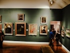 Selection of oil paintings and prints displayed together in a warm gallery setting