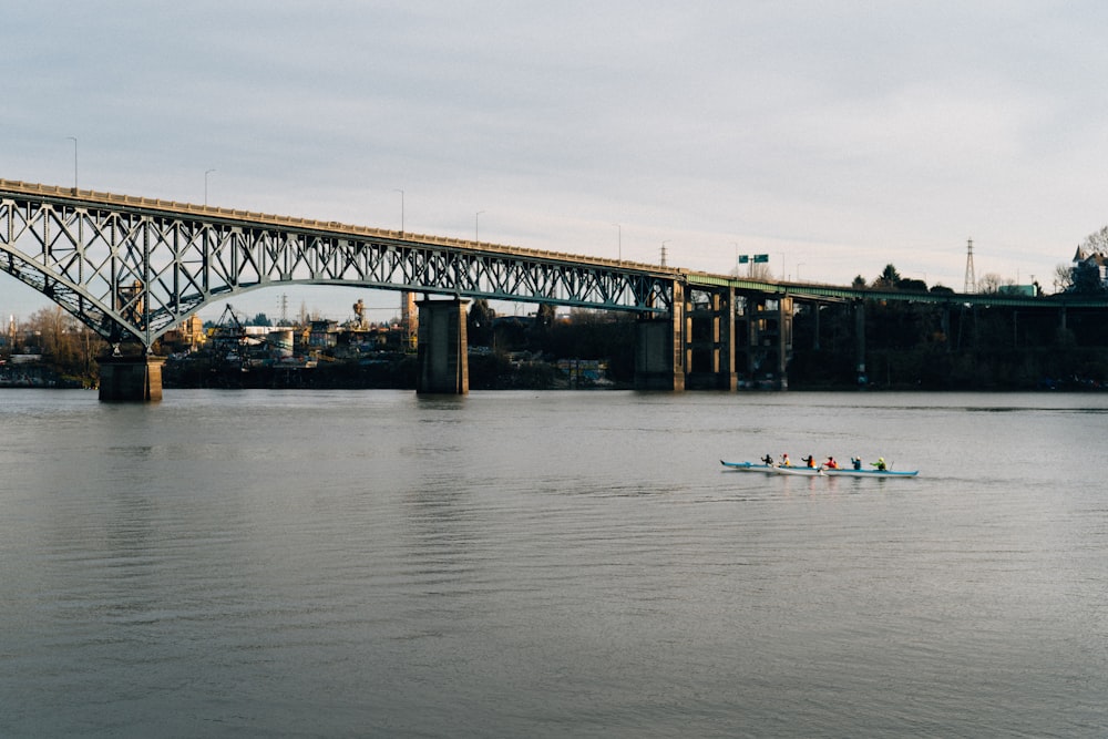 a group of people rowing a boat under a bridge