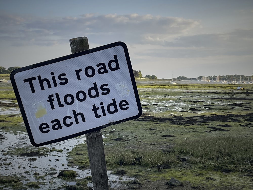this road floods each tide sign posted on a wooden post