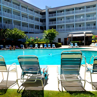A family enjoying a sunny day by a spacious rectangular pool with lounge chairs.