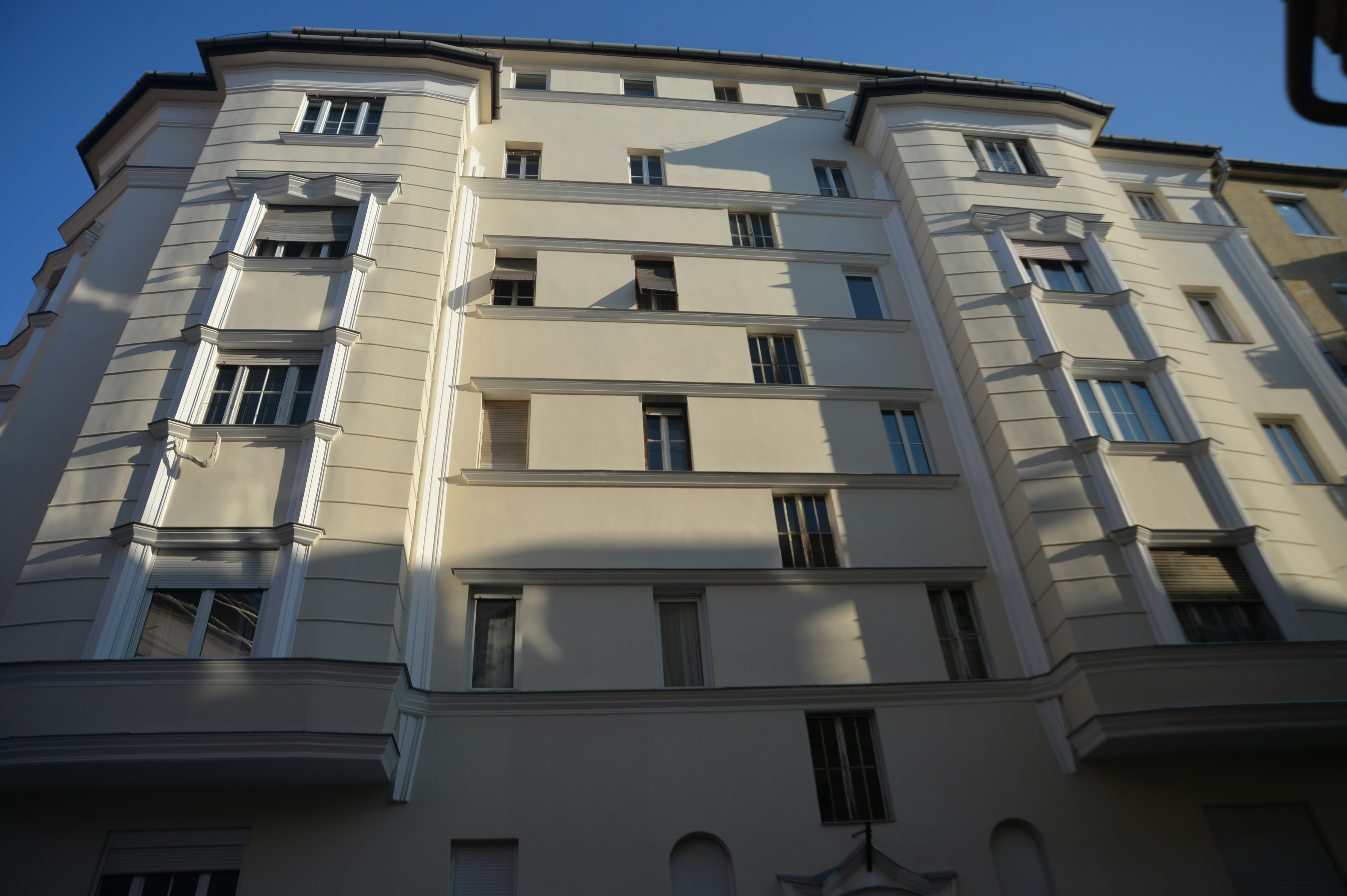 Modern luxury apartment building with glass facade, clear blue sky, contemporary architecture