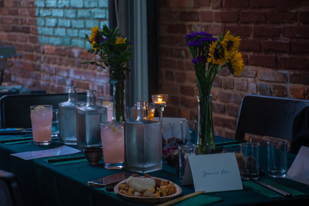 a table topped with a plate of food and vases of flowers