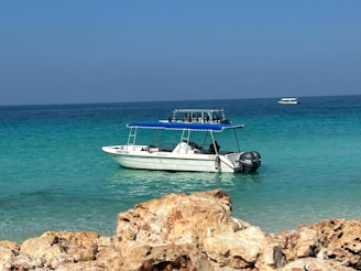 A motorboat anchored in a crystal-clear turquoise bay with swimmers enjoying the water