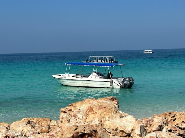 A motorboat anchored in a crystal-clear turquoise bay with swimmers enjoying the water