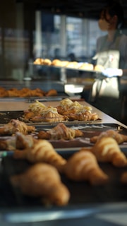 Smiling baker presenting a freshly baked batch of croissants in a cozy bakery setting