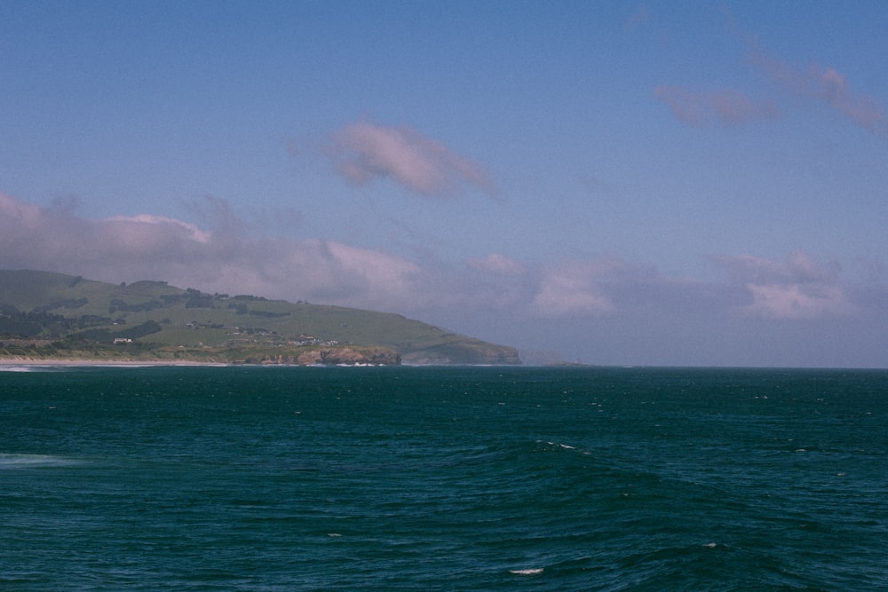 a large body of water with a hill in the background