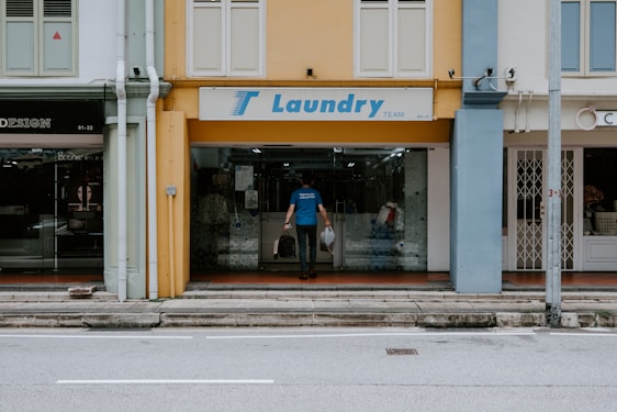 A friendly staff member carefully washing clothes and shoes in a bright, clean laundry shop.
