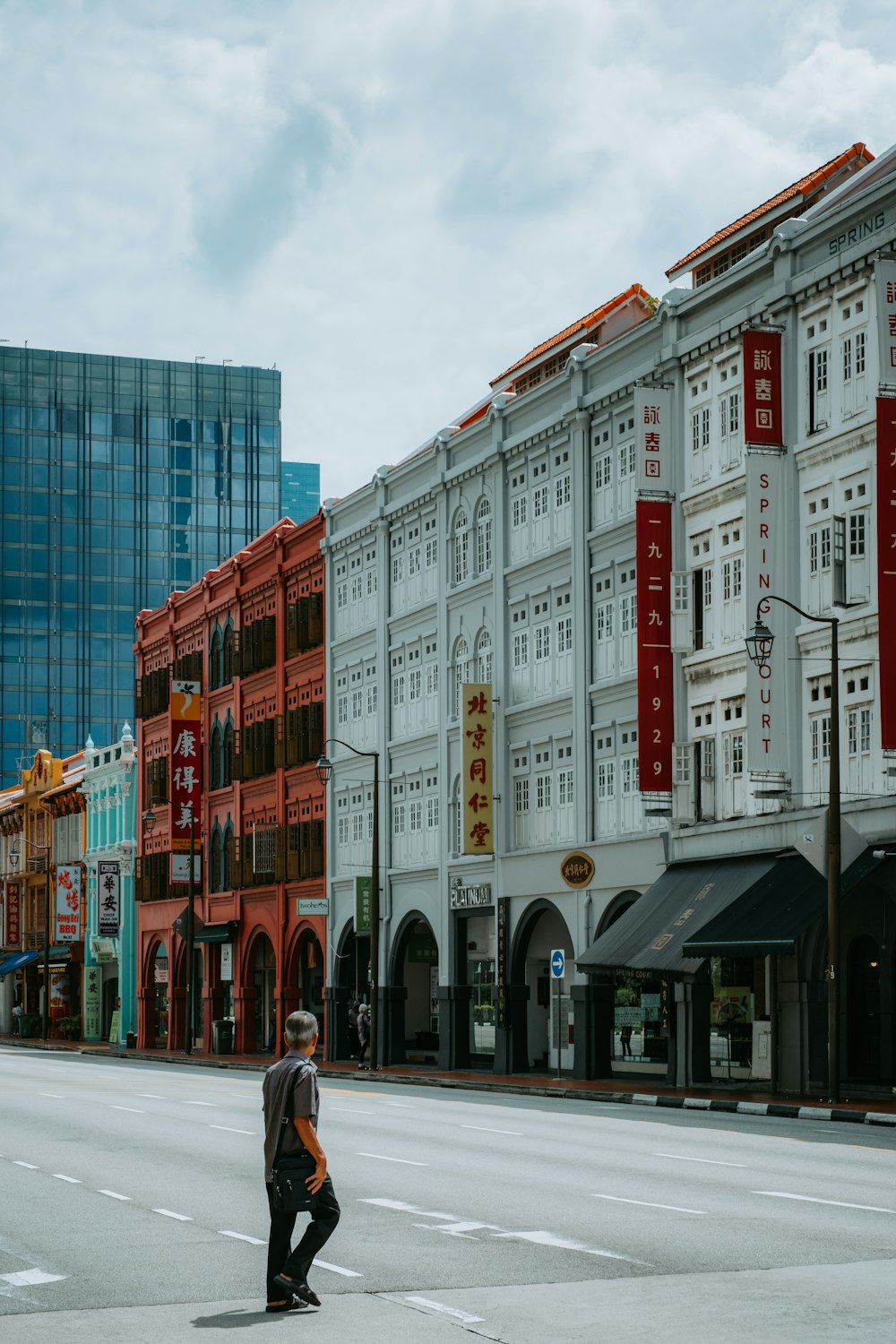 a man walking across a street in front of tall buildings