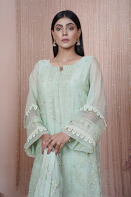 Elegant model wearing a pure silk Punjabi suit with delicate hand-painted patterns in antique gold, standing against a muted backdrop.