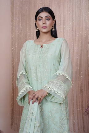 A graceful model wearing a premium handmade Indian ethnic dress, standing against a soft neutral background.