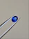 Close-up of a radiant blue sapphire gemstone resting on a velvet cushion.