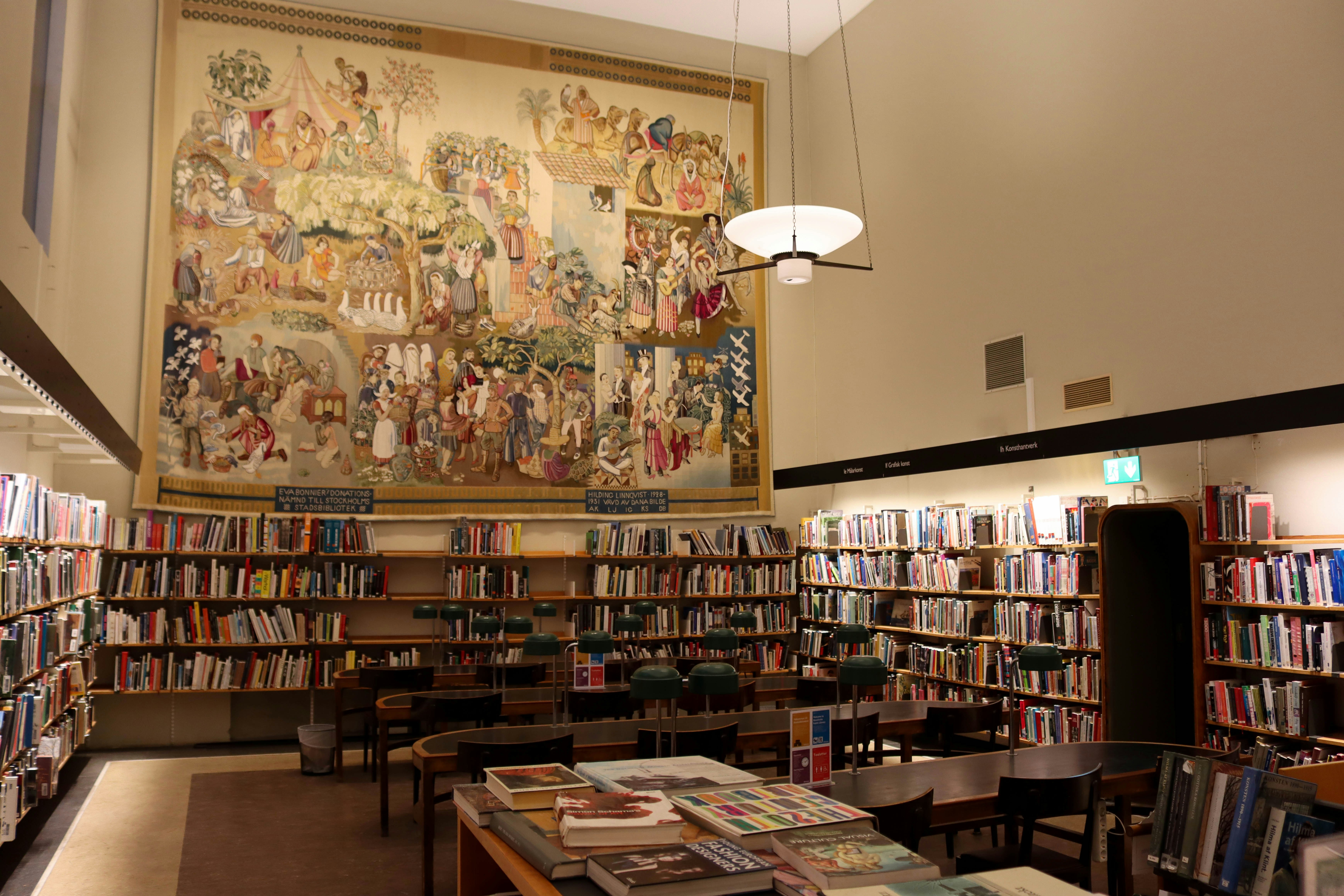 a library filled with lots of books under a painting