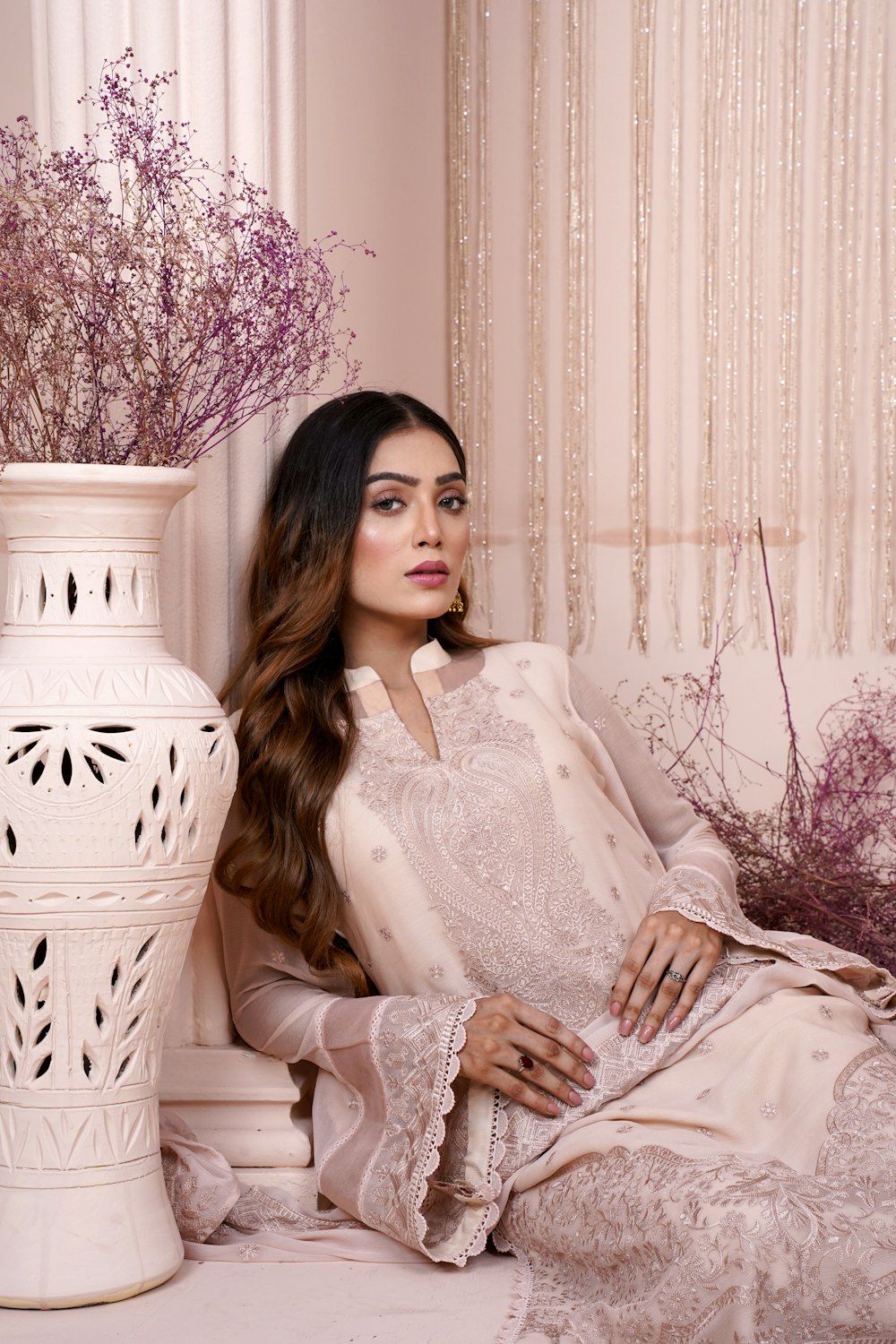 a woman sitting on a couch next to a vase